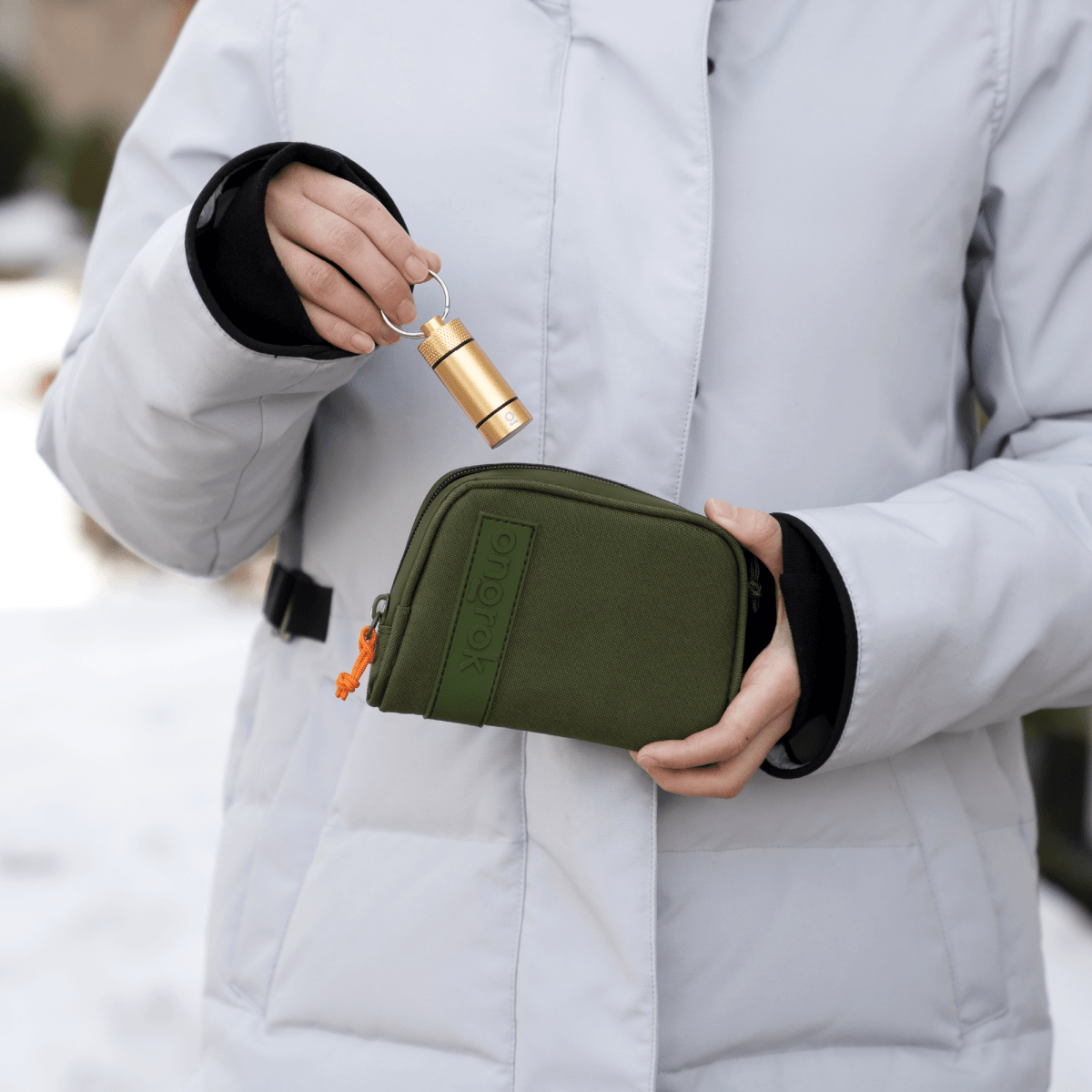 A hand holds the Carbon-lined Wallets with Combination Lock V 2.0 against a light gray jacket, showing its compact size.