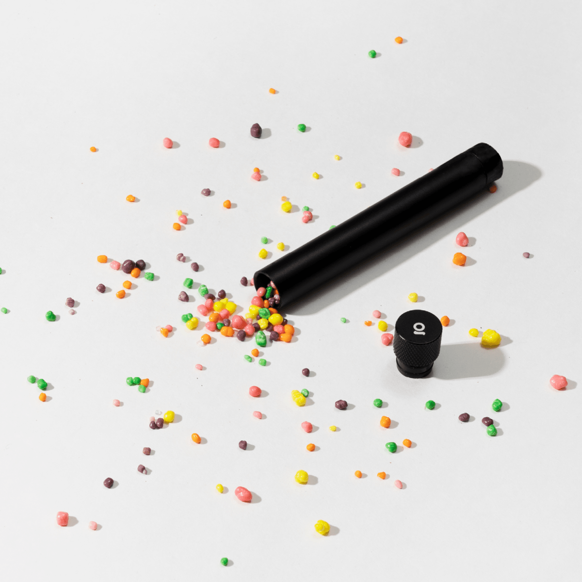 A top-down view of the Premium Storage Tube  Single, tipped on its side with colorful granules spilling onto a clean white surface.