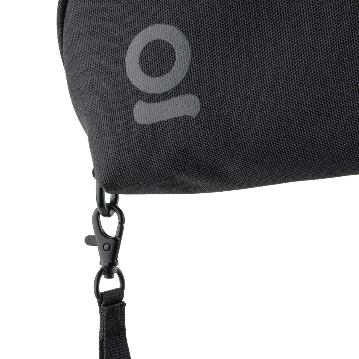 Close-up view of the Carbon-lined Wrist Bag’s black strap and clip, hanging against a dark background.