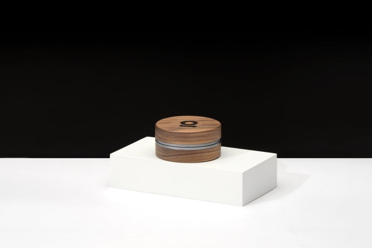 A centered, front view of the 3 Inch, 2-Piece Walnut Grinder atop a white pedestal, highlighting its cylindrical form.