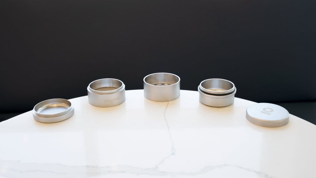 A top-down view of the 5 Piece Storage Grinder set, arranged on a white surface with soft, diffused lighting.