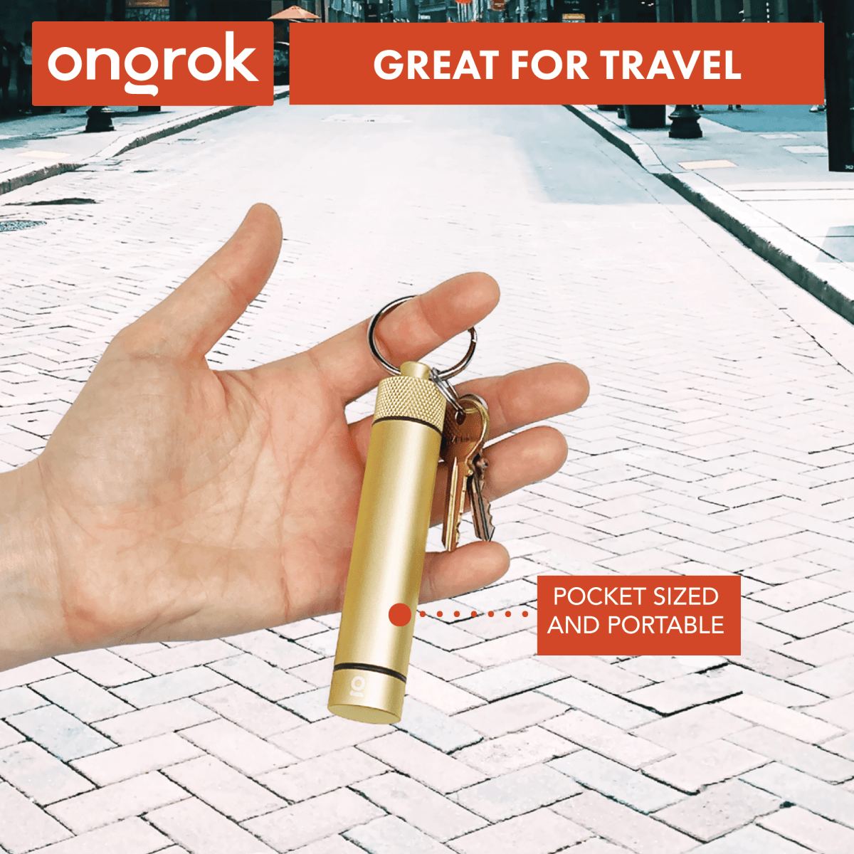 A hand holds the Onnorok Aluminum Storage Keychain against a blurred street background.