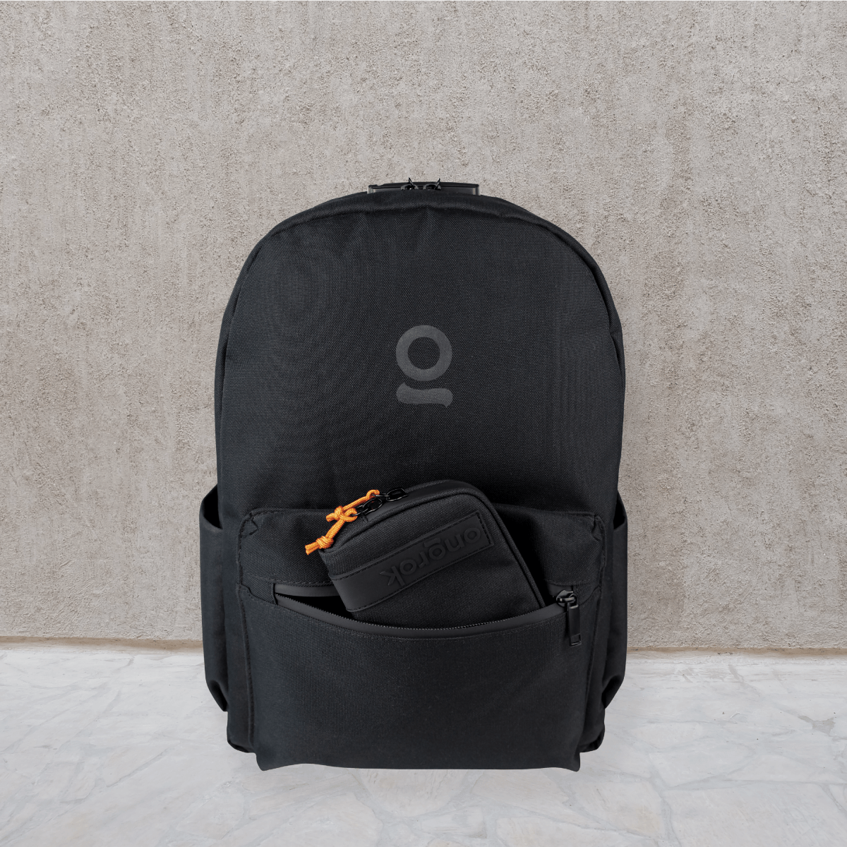 Front view of the Carbon-lined Backpack on a light gray surface, featuring a black exterior and subtle branding.