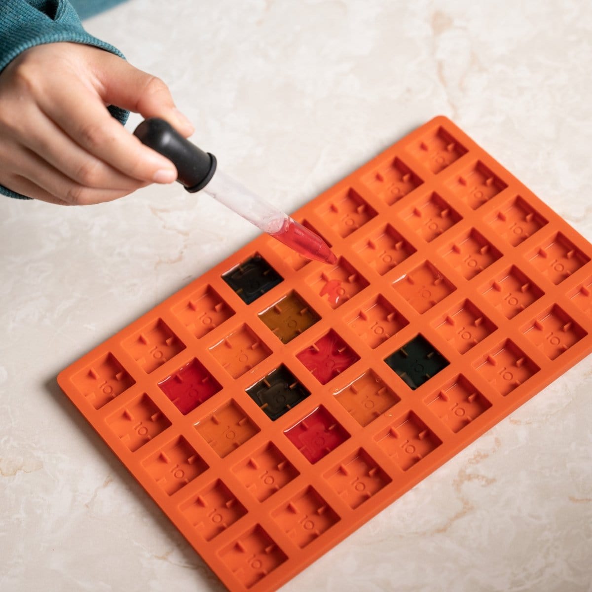 A top-down view of the Scored Gummy Molds filled with colorful candies on a white surface.