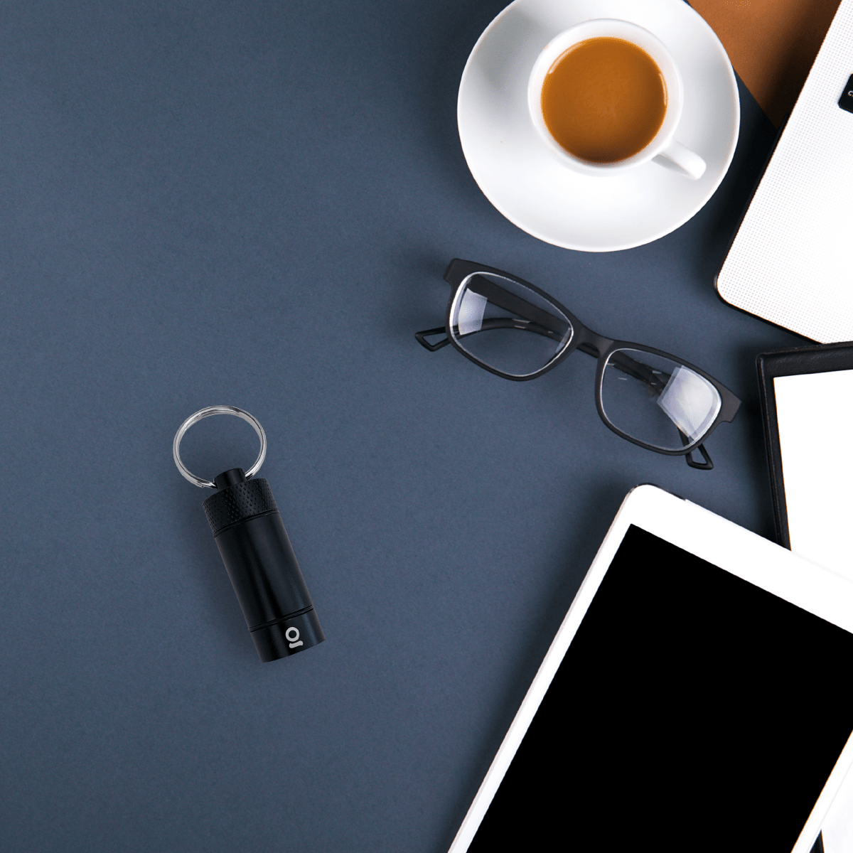 Overhead view featuring the Small Storage Keychain next to eyeglasses and a cup of coffee on a light surface.