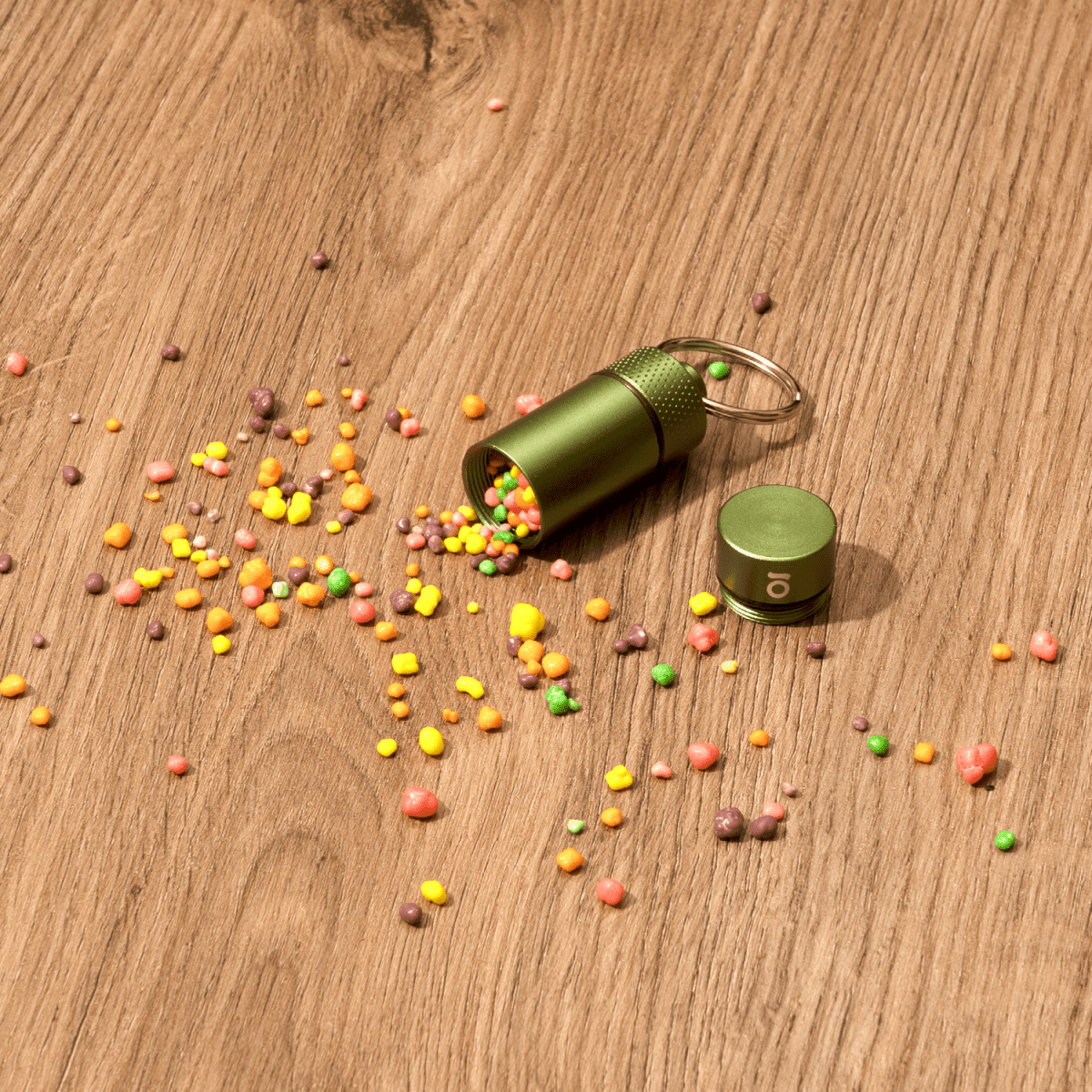 A top-down view of the Small Storage Keychain, spilling colorful contents onto a textured wooden surface.