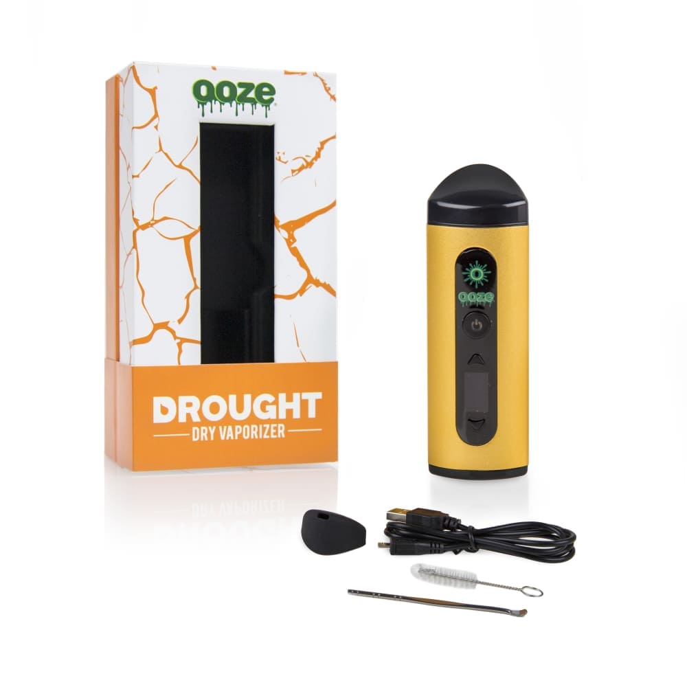 Front view of the Ooze Drought Dry Herb Vaporizer Kit with its charging cable and a small cleaning brush next to its packaging.