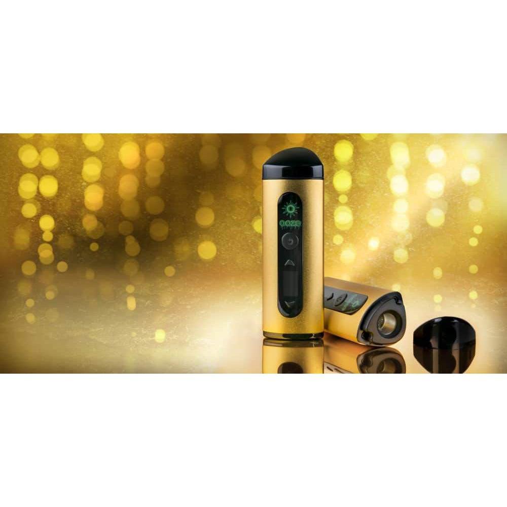 A low-angle shot displays the Ooze Drought Dry Herb Vaporizer Kit against a blurred golden backdrop with light reflections.