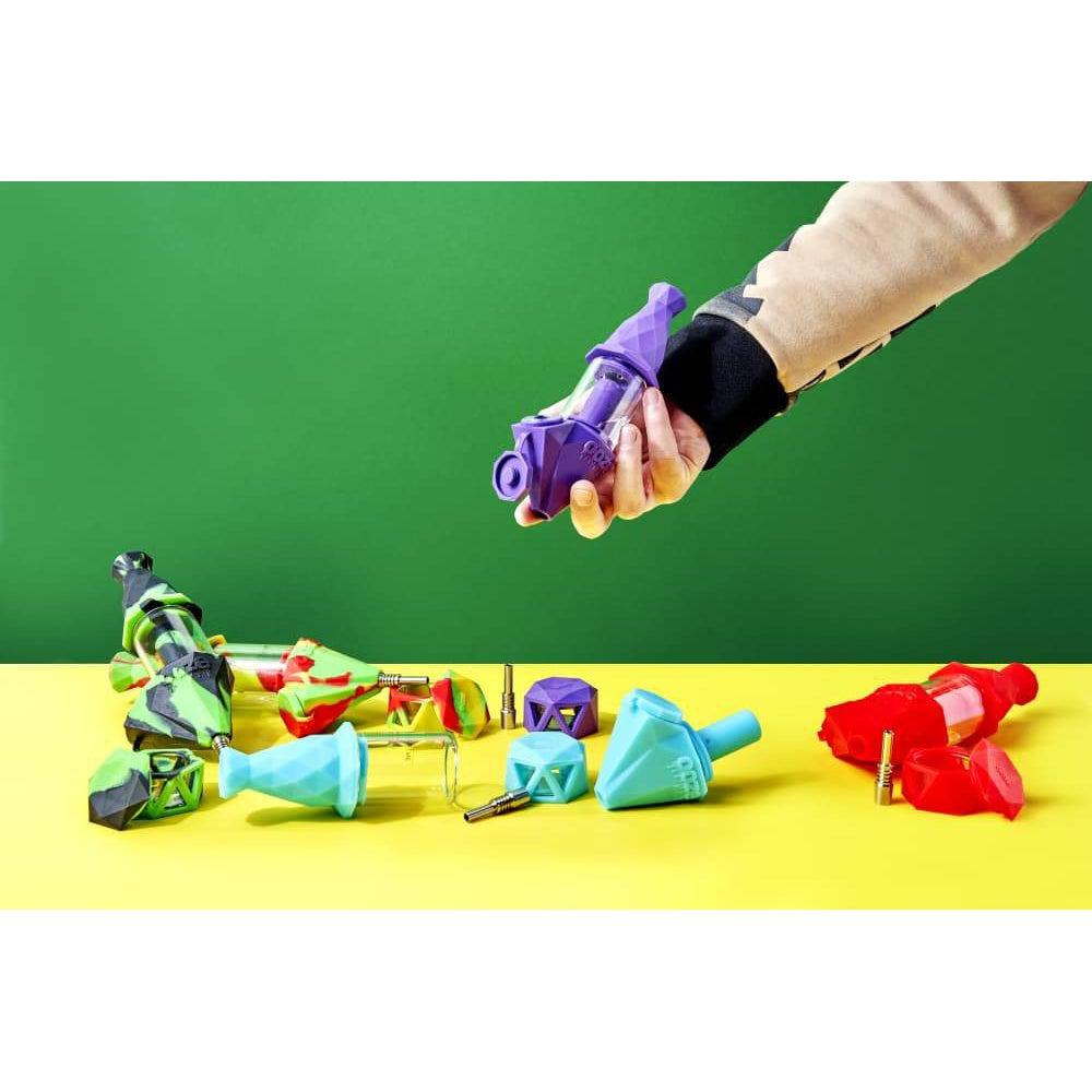 A hand holds the Ooze Bectar Silicone Water Pipe and Concentrate Straw against a vibrant green backdrop.