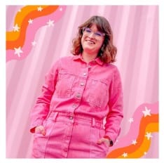 Woman smiling with hands in pockets against a pink striped backdrop, wearing a pink jumpsuit in the Prism Flower Power Beaker Single Stack image.