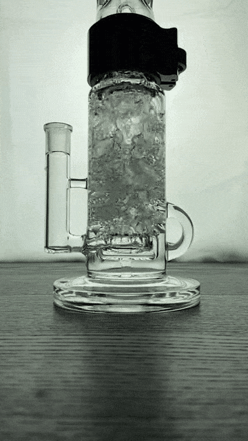 Low-angle view of the Prism Klein Incycler Single Stack showing its cylindrical, ice-filled central chamber and clear glass base against a softly lit background