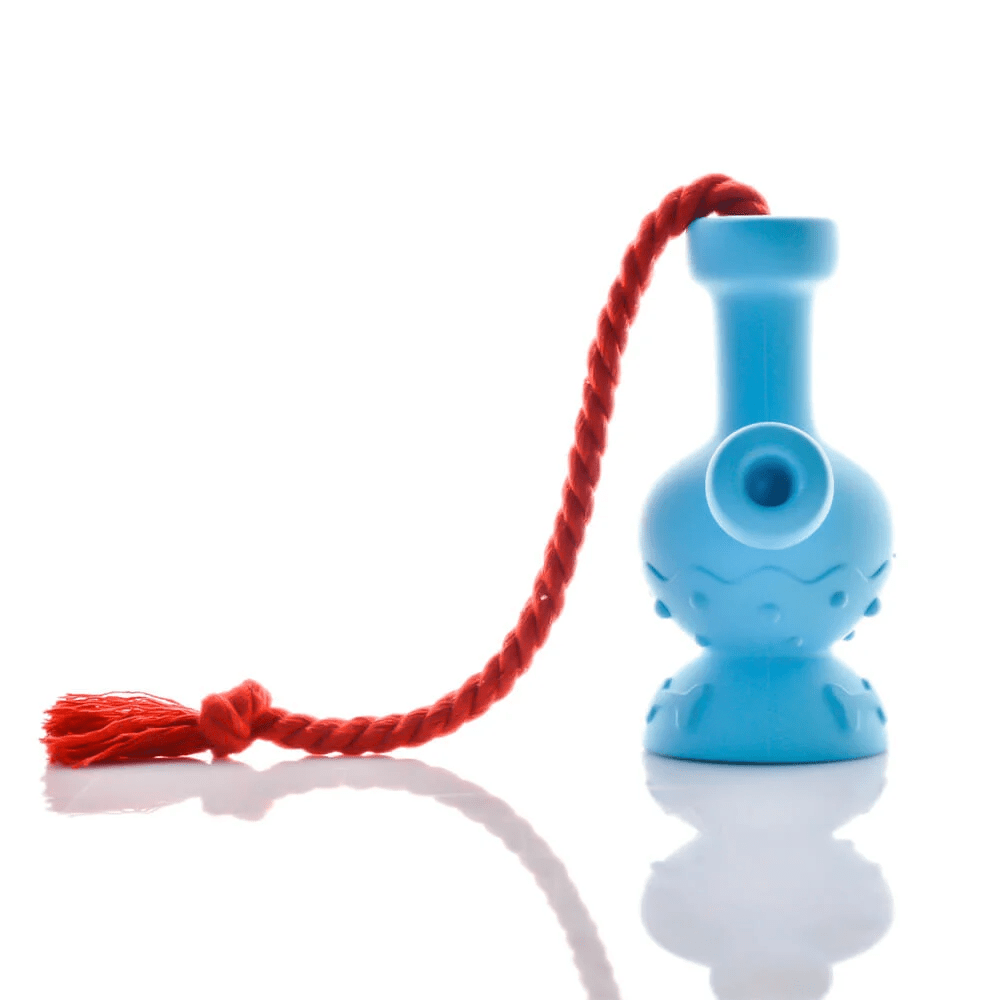 Side view of a blue Tug & Toke with a red twisted rope draped over its neck, reflected on a bright white surface.
