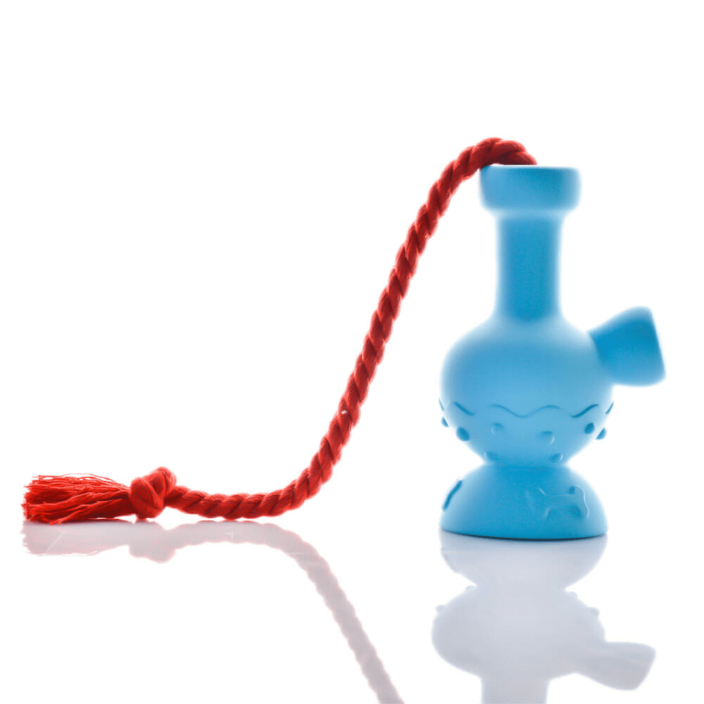 Side view of a blue Tug & Toke with a red braided tassel draped over its neck, shot on white with a soft reflection.