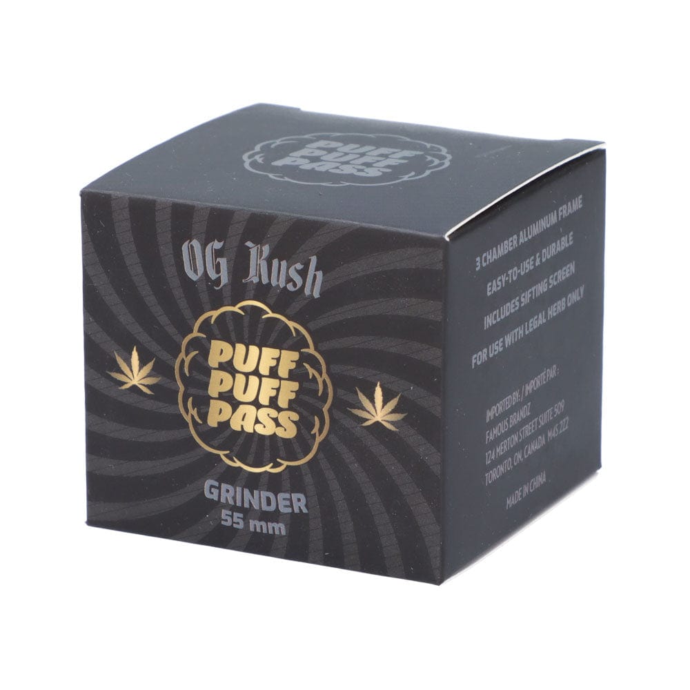 Three-quarter front view of the Puff Puff Pass OG Kush 55mm 3-Stage Grinder boxed in black packaging with gold logo and subtle spiral background.