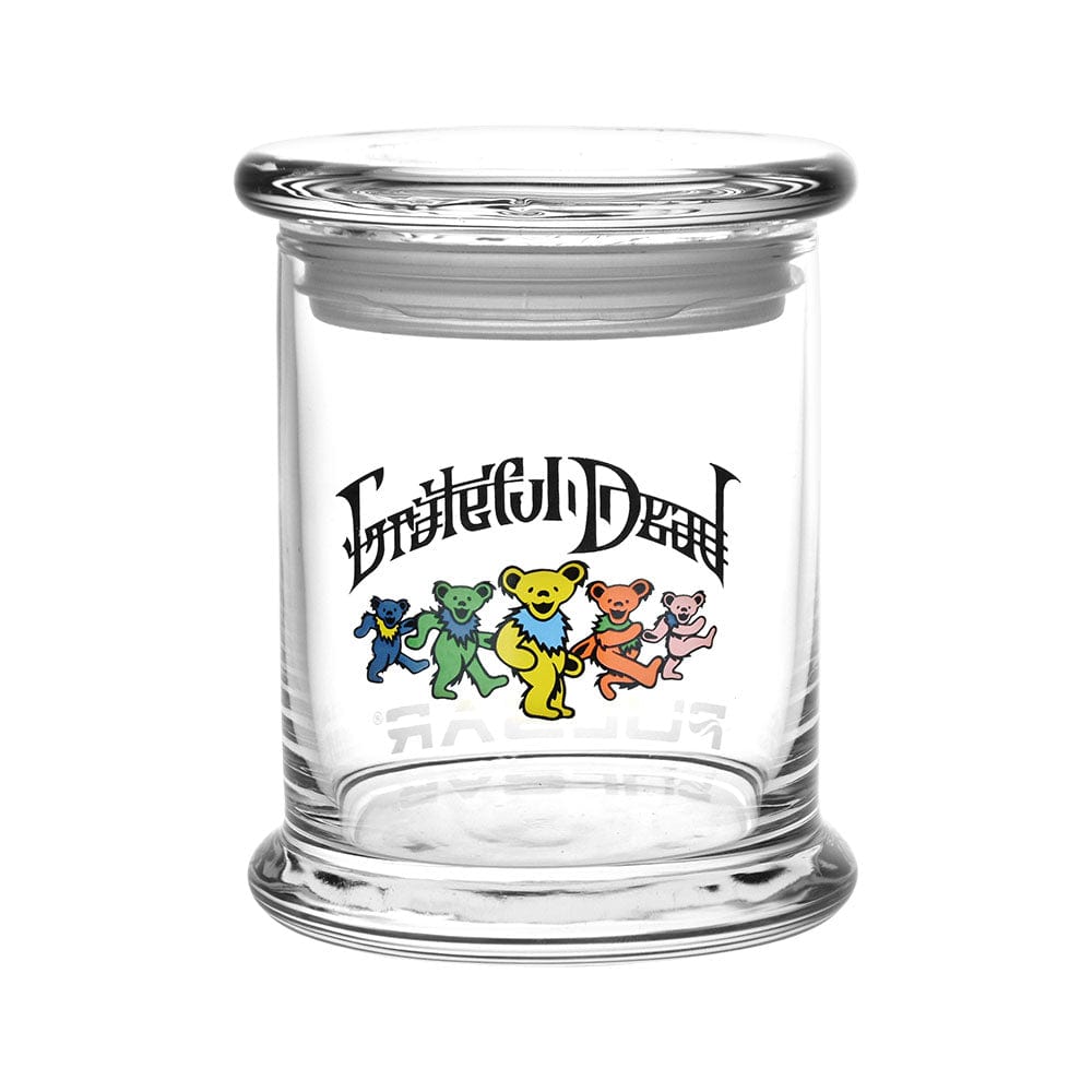 A front view of the Grateful Dead x Pulsar Pop Top 1/2oz Jar, showcasing its clear glass construction and simple, cylindrical shape.
