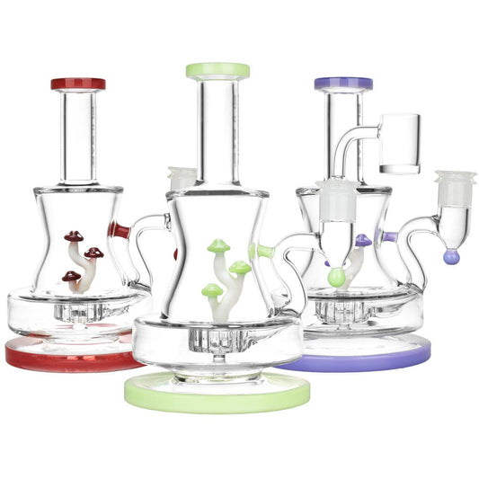 A front view of the Pulsar Shadow Lurking Shrooms Dab Rig showcasing colorful mushroom-shaped accents on a clear glass base.