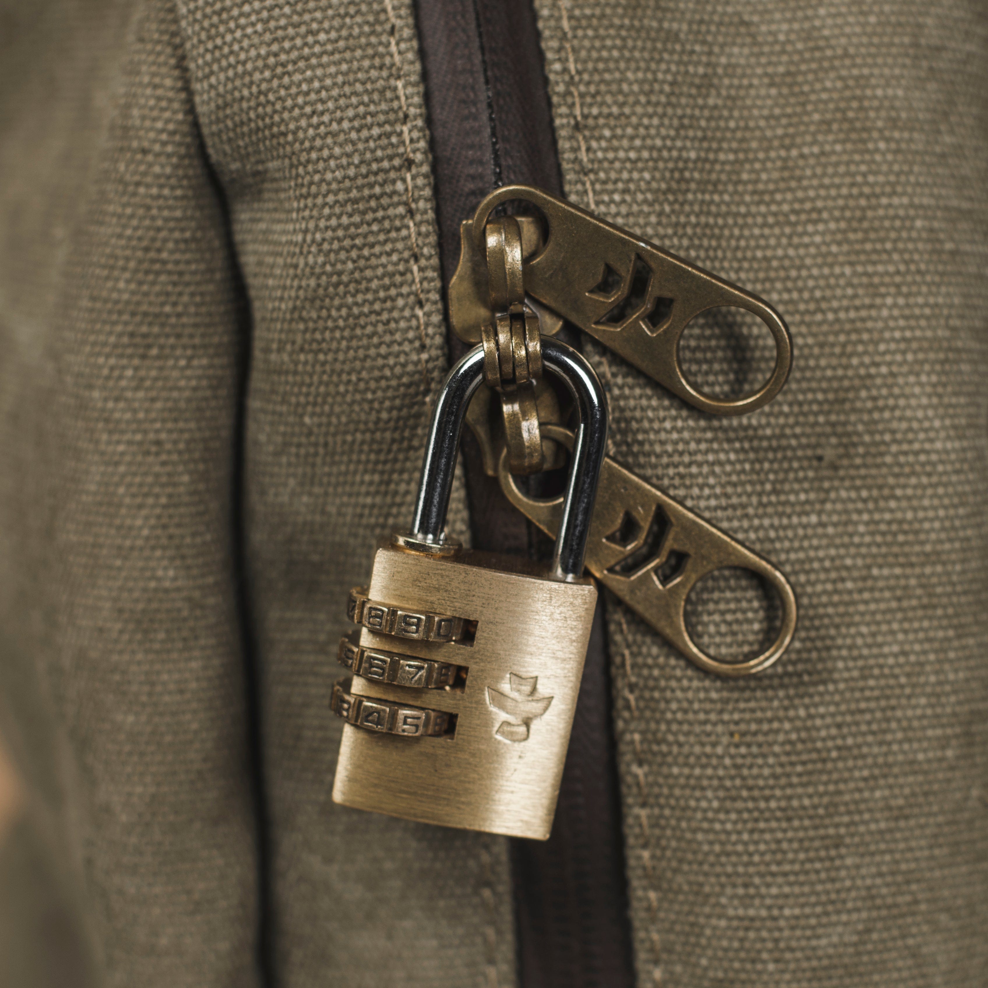 Close-up view of The Explorer - Smell Proof Backpack’s zipper pull, featuring a bronze-toned lock with numbers visible.