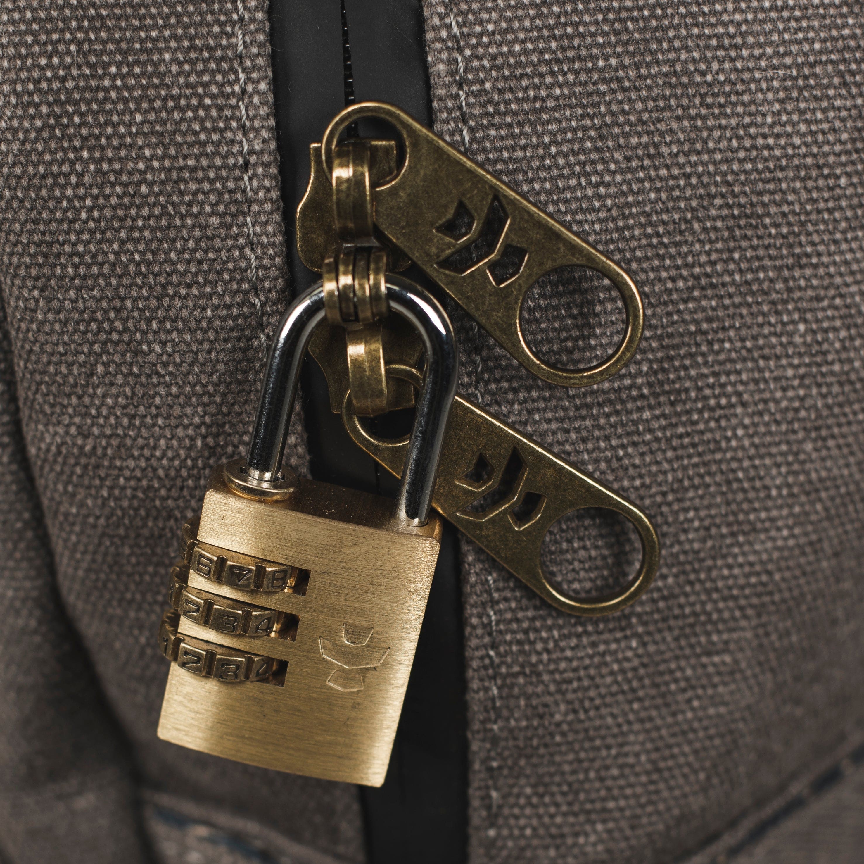 Close-up view of The Explorer - Smell Proof Backpack's zipper pull against a textured gray background.