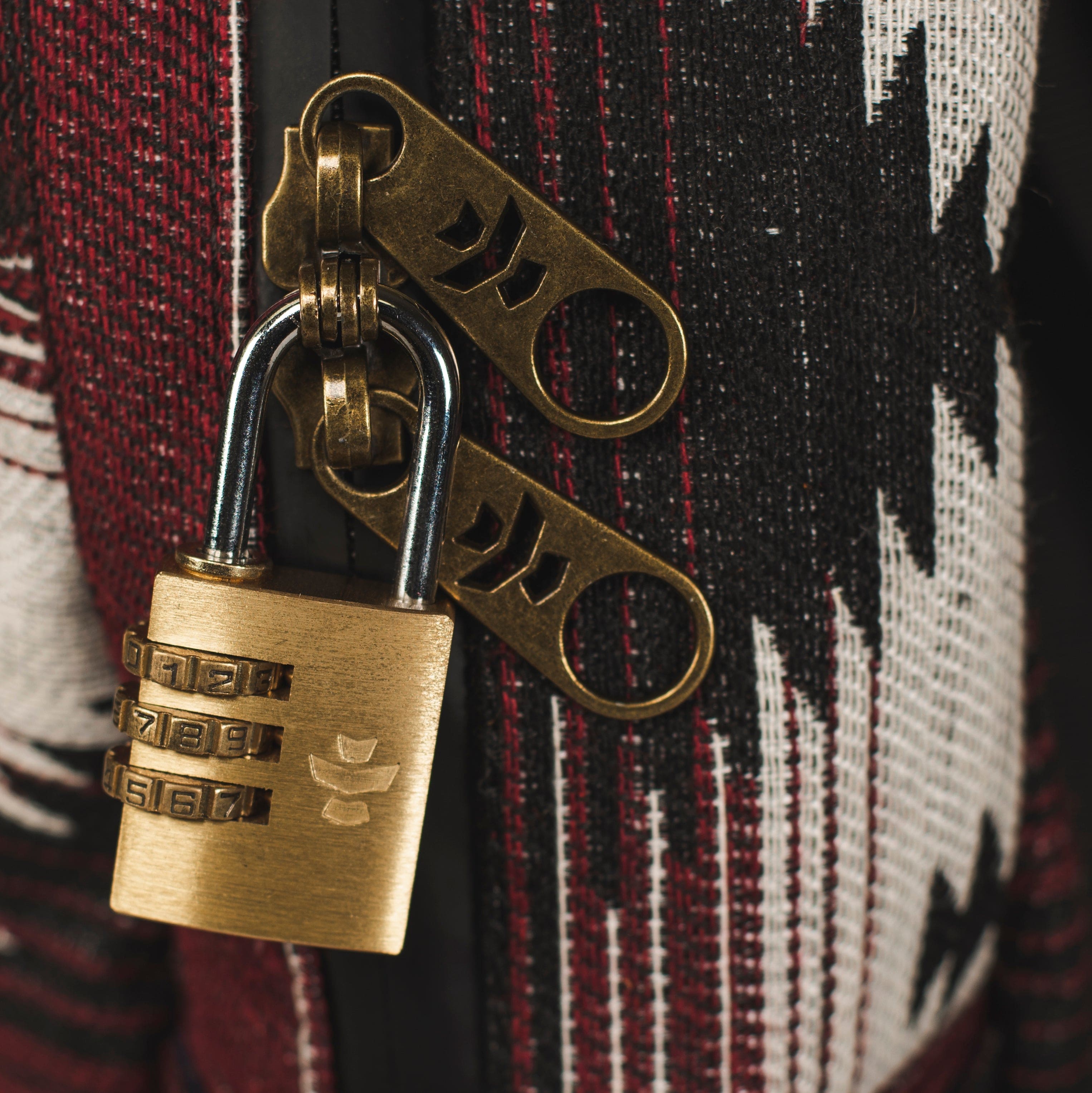 Close-up view of The Explorer - Smell Proof Backpack’s zipper pull against a patterned fabric background.