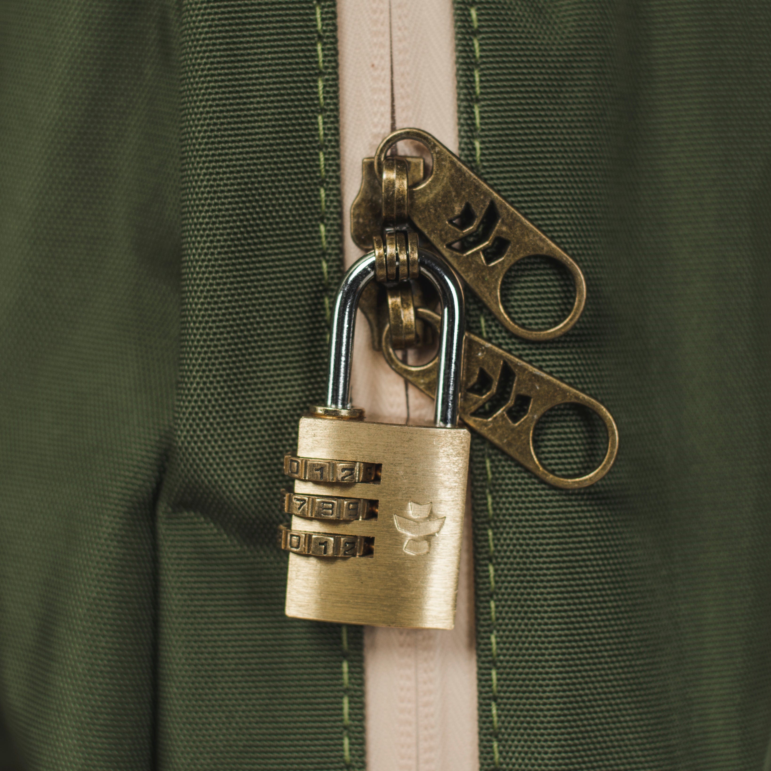Close-up of The Explorer - Smell Proof Backpack’s zipper pull, with a metal lock and dark green canvas texture.