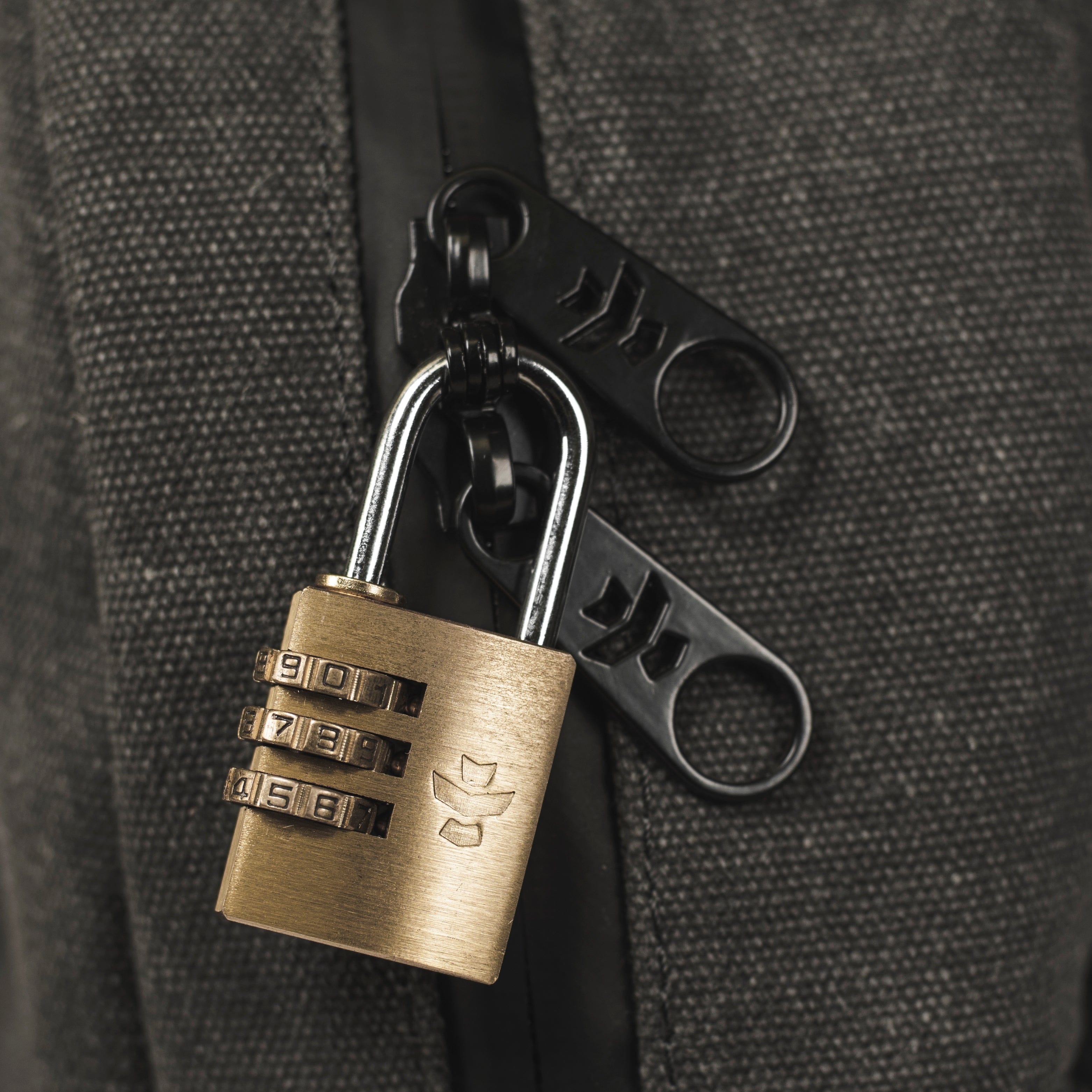 Close-up of the Explorer - Smell Proof Backpack’s lock, set to a combination, against a dark, textured background.