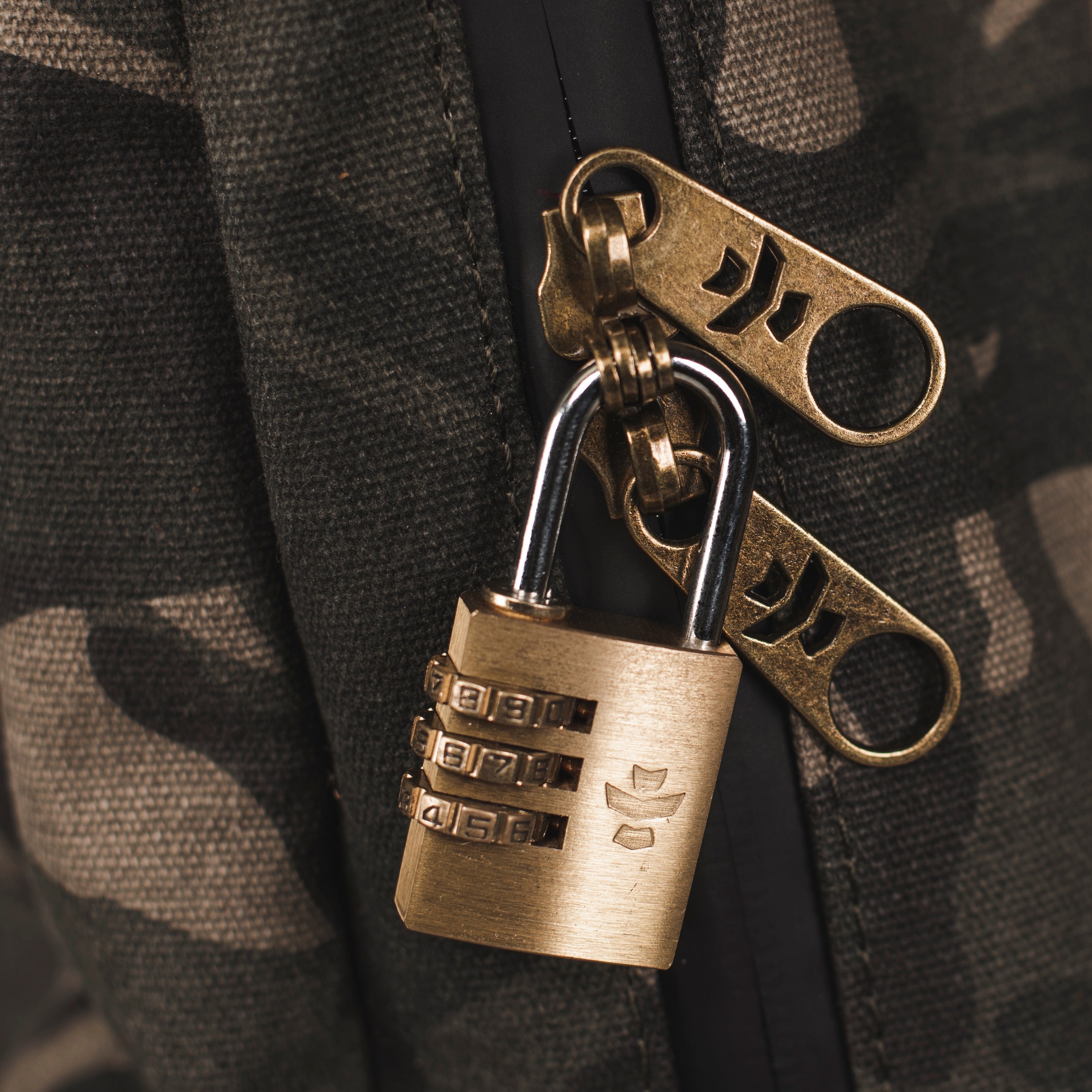 Close-up view of The Explorer - Smell Proof Backpack's metallic zipper pulls against a dark, textured background.