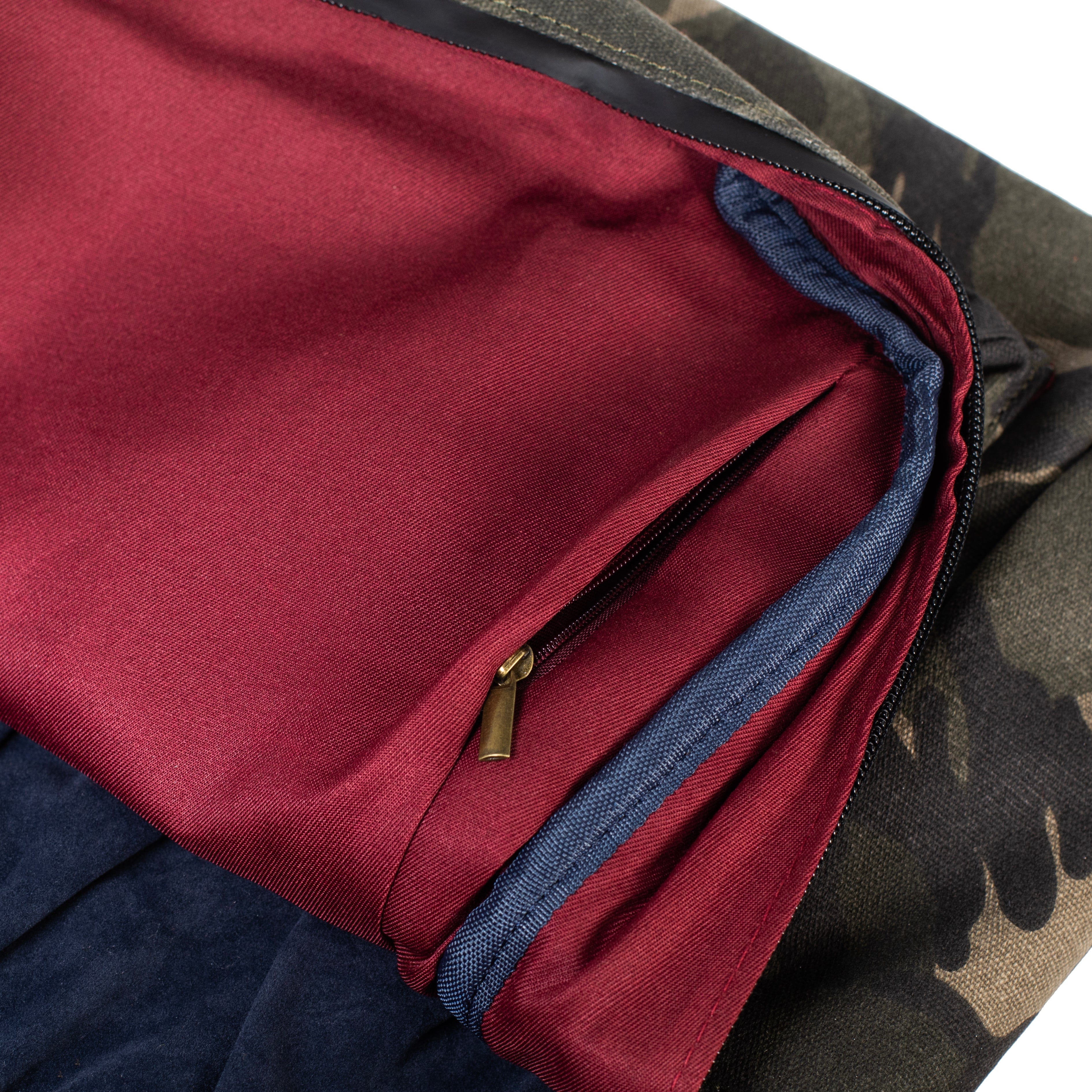 A close-up view inside The Explorer - Smell Proof Backpack, revealing a deep maroon interior with a blue zipper detail.