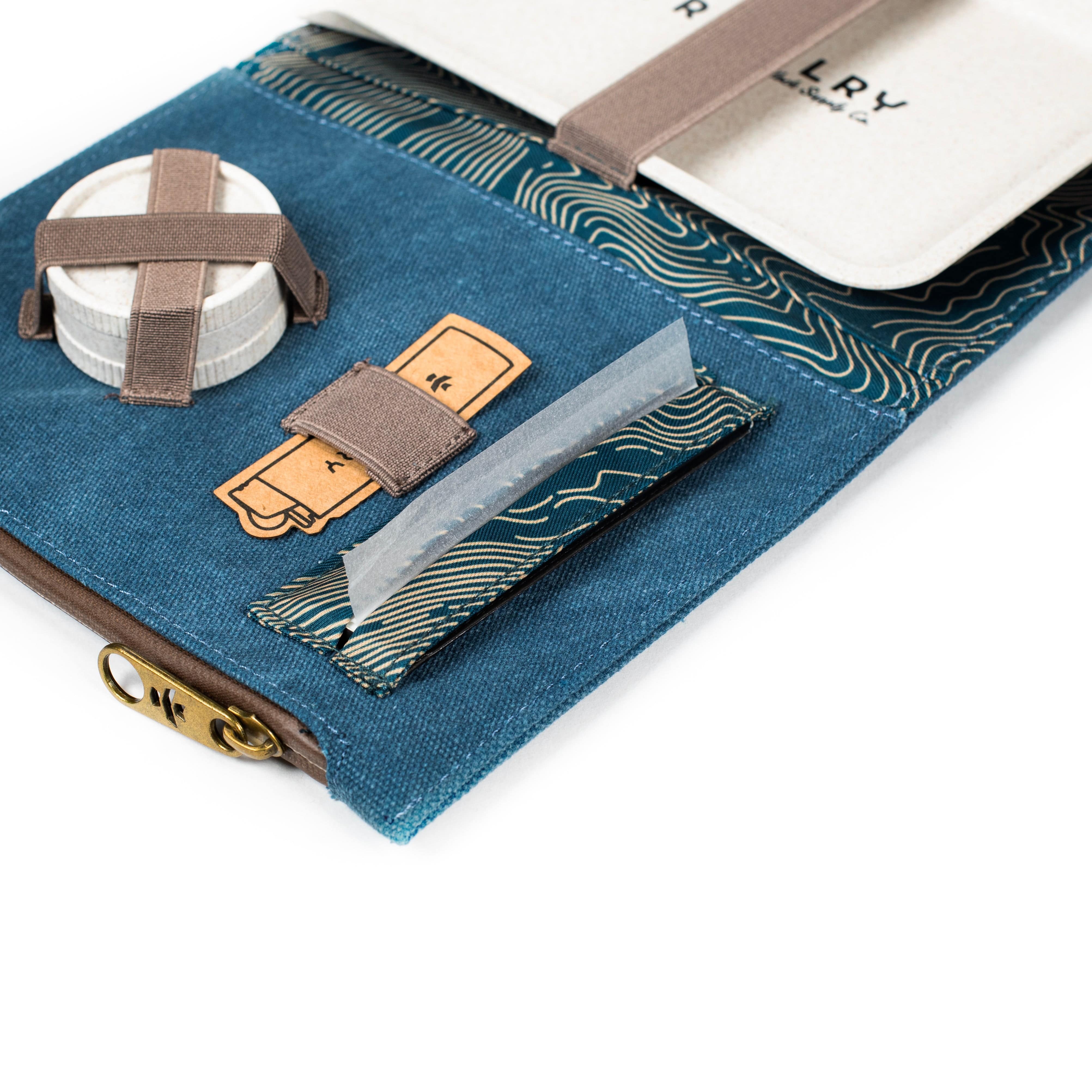 Close-up angled view of The Rolling Kit - Smell Proof Kit, showcasing a navy and charcoal kit with a branded leather patch.