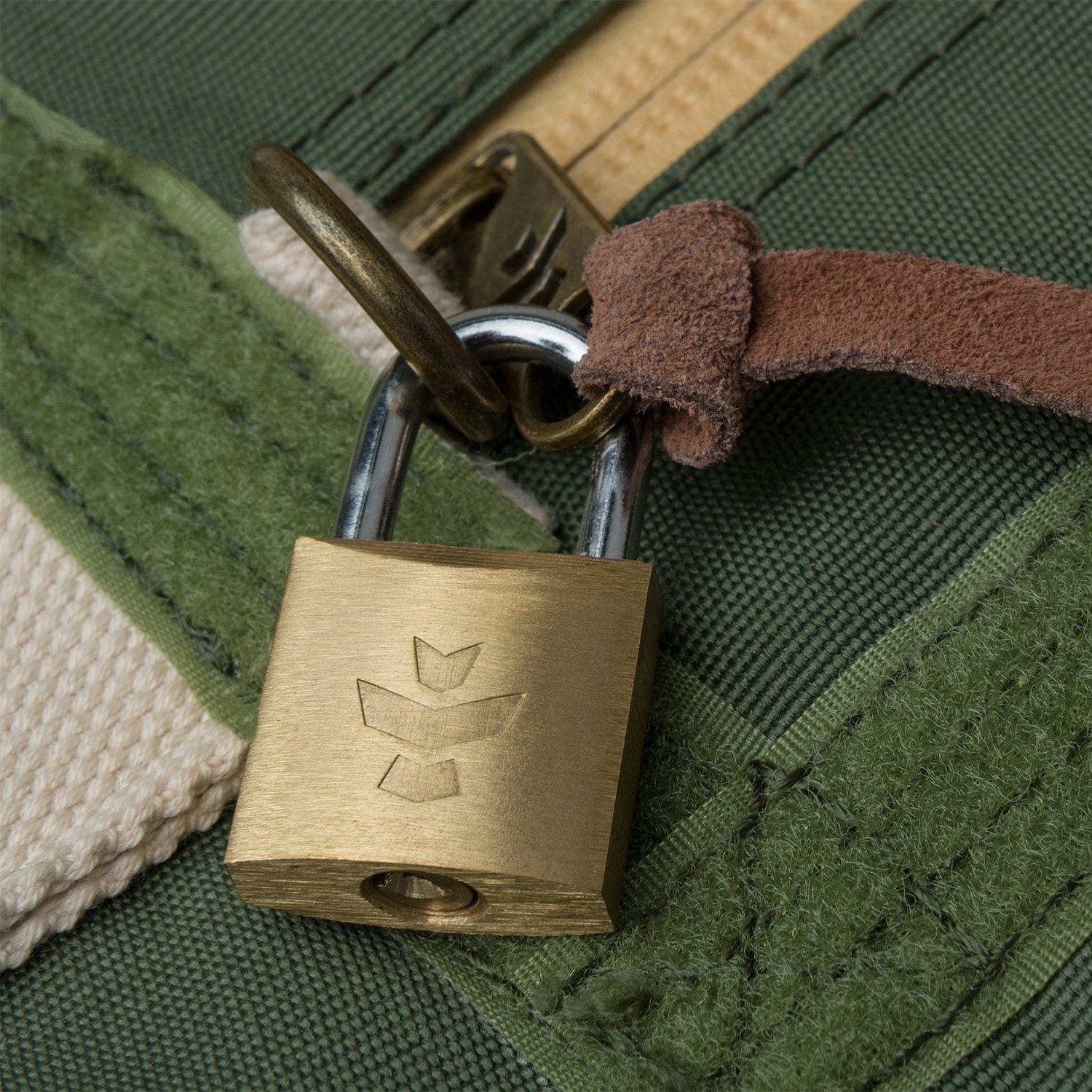 Close-up of a brass padlock fastened to green canvas straps on The Weekender - Smell Proof Medium Duffle.