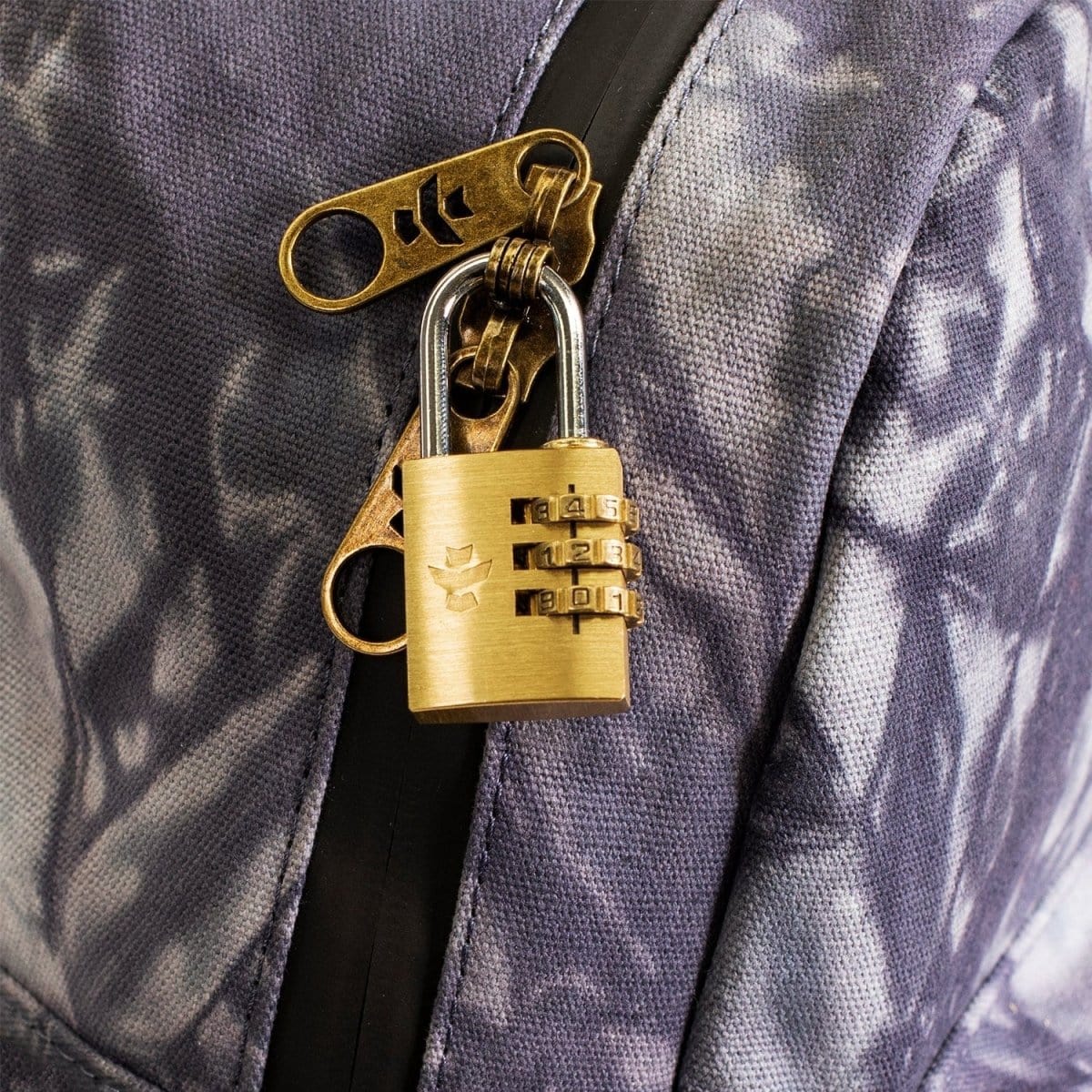 Close-up of The Shorty - Smell Proof Mini Backpack’s zipper pull, featuring a detailed metallic design against a dark fabric background.