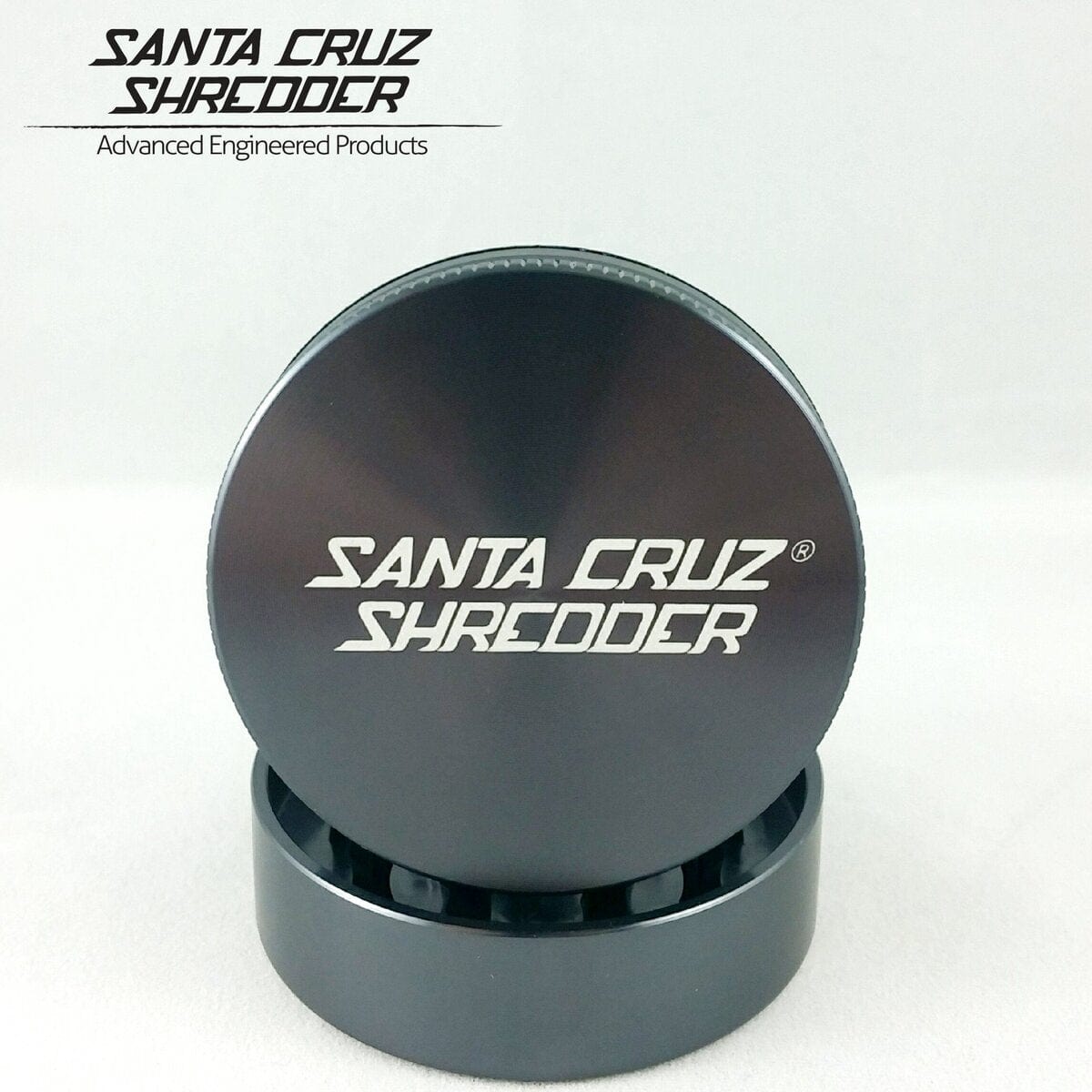 Close-up of the Santa Cruz Shredder 2 Piece Large Grinder, showing its multi-tiered metal construction and circular shape.