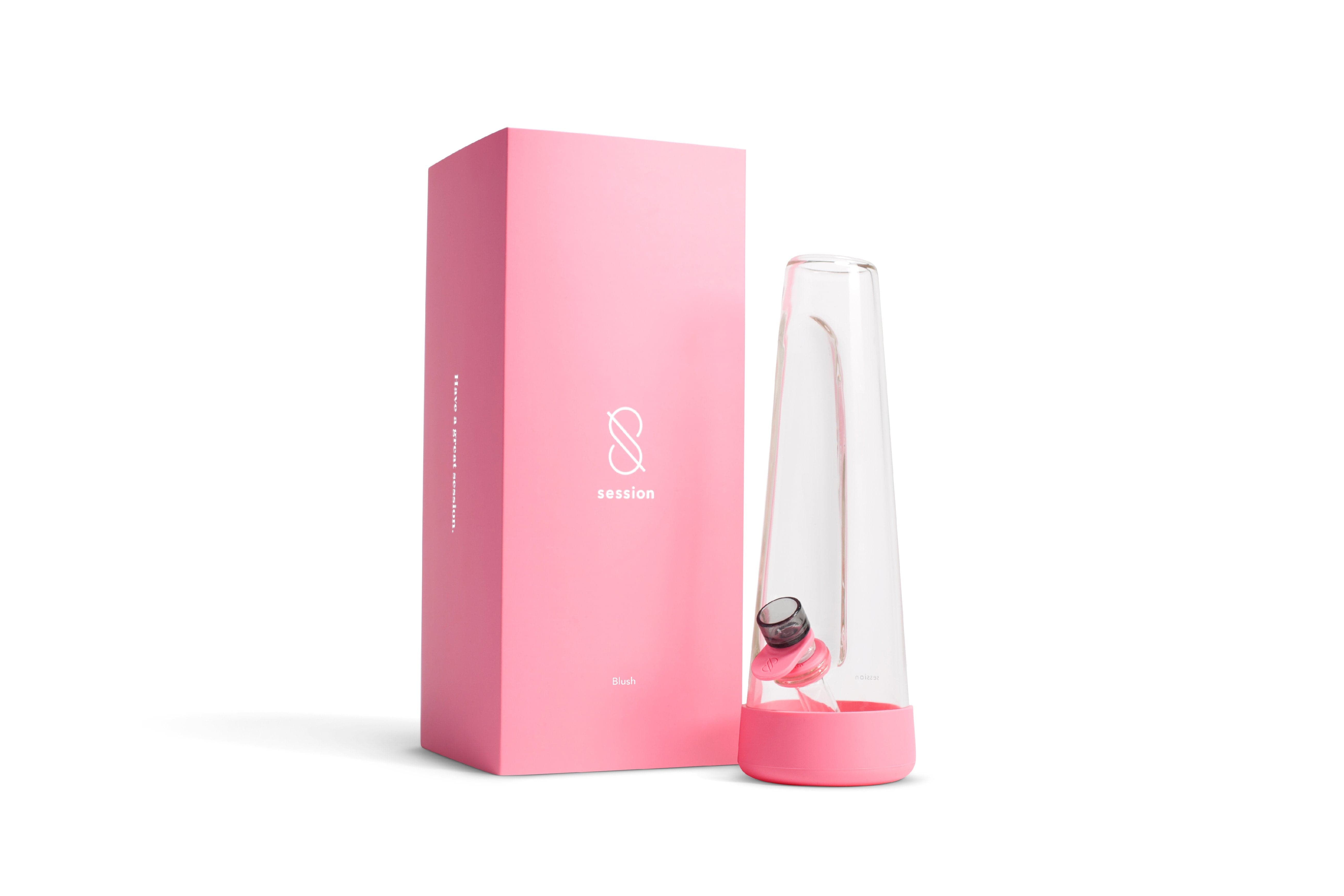 Angled front view of the clear Session Goods Modern Bong beside its pink rectangular box on a white background.
