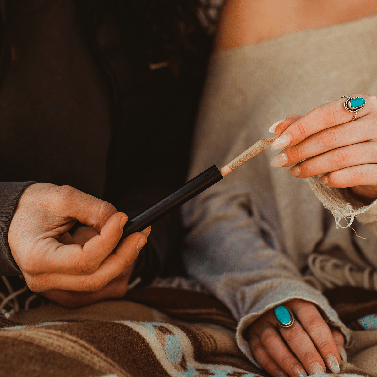 Close-up view of hands holding the StashLight - Doob Tube & Refillable Lighter, with a textured knit background.