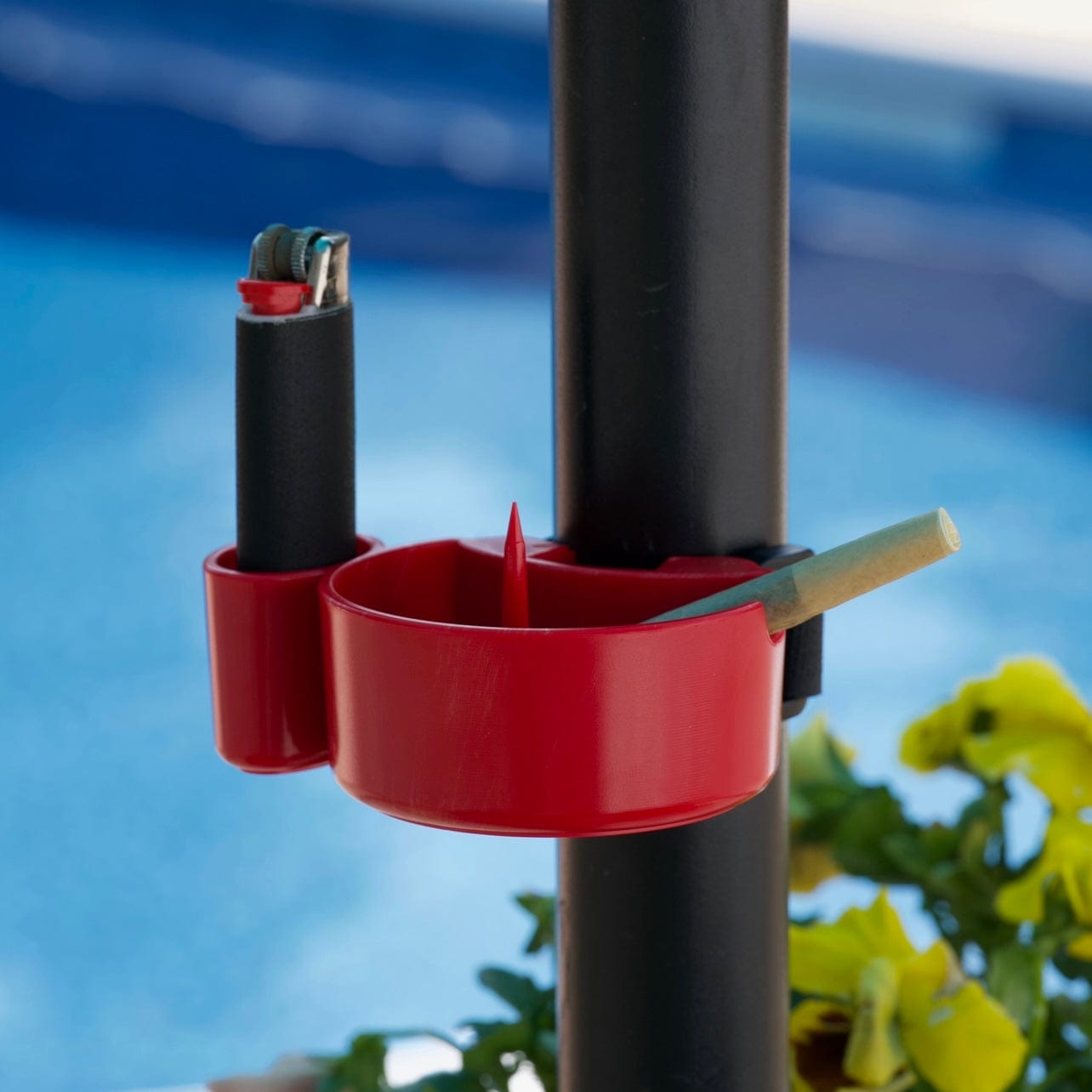 A close-up view of the TreeHouse AshTray mounted on a dark pole, with a partially smoked cigarette resting inside.