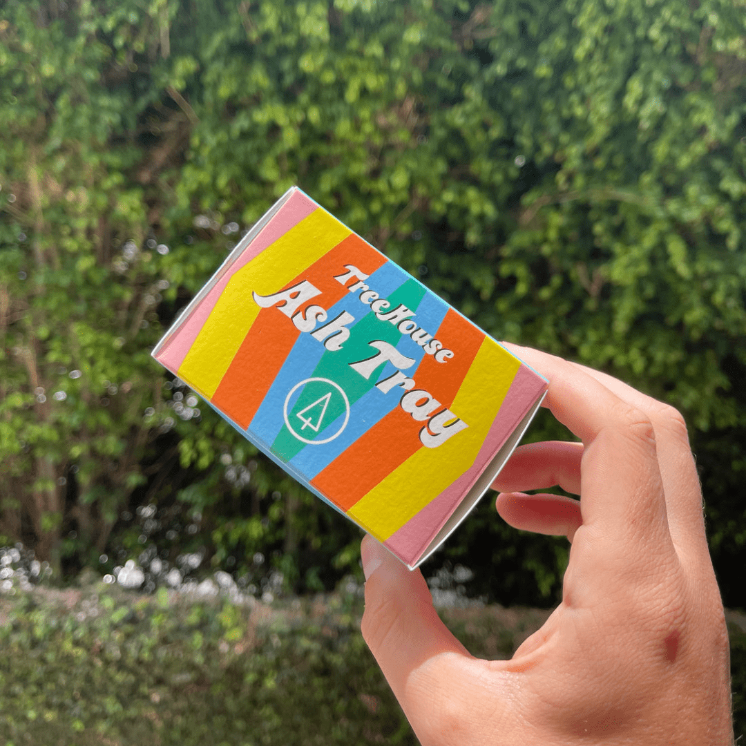 Front view of the TreeHouse AshTray, a round, ceramic dish presented against a blurred green background.