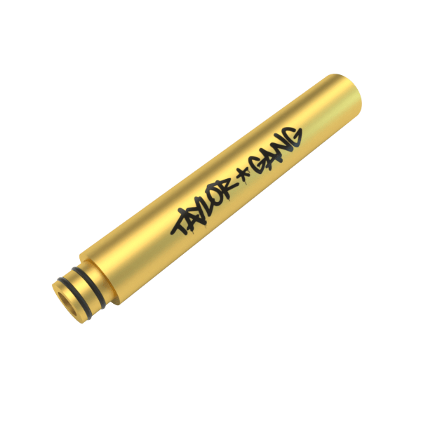 Angled close-up of a gold Taylor Gang x Stundenglass Wand showing its cylindrical body and black logo against a white background
